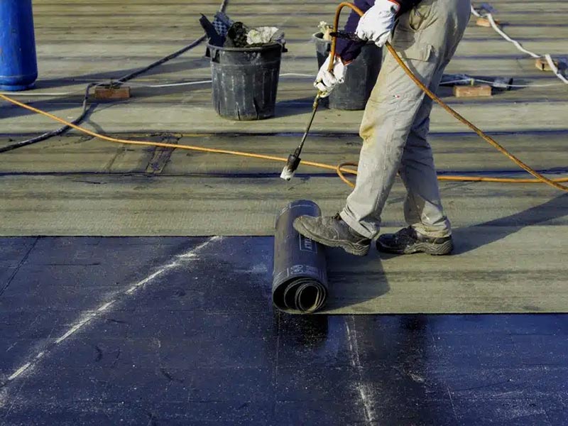 Worker Preparing bitumen roofing felt roll