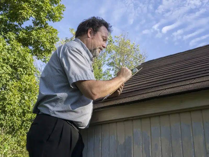 Person checking Hail damage done to a roof